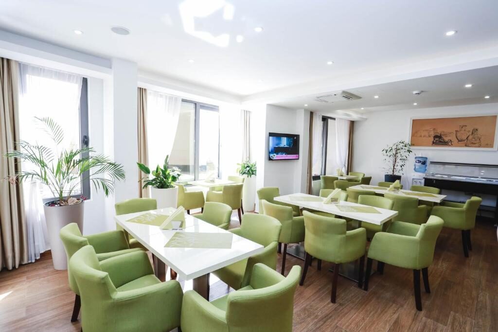 Breakfast room with green chairs and white tables at Arka Budva
