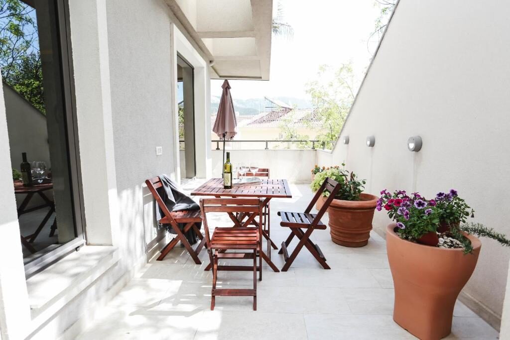 Terrace with wooden furniture and flowers at Arka Budva
