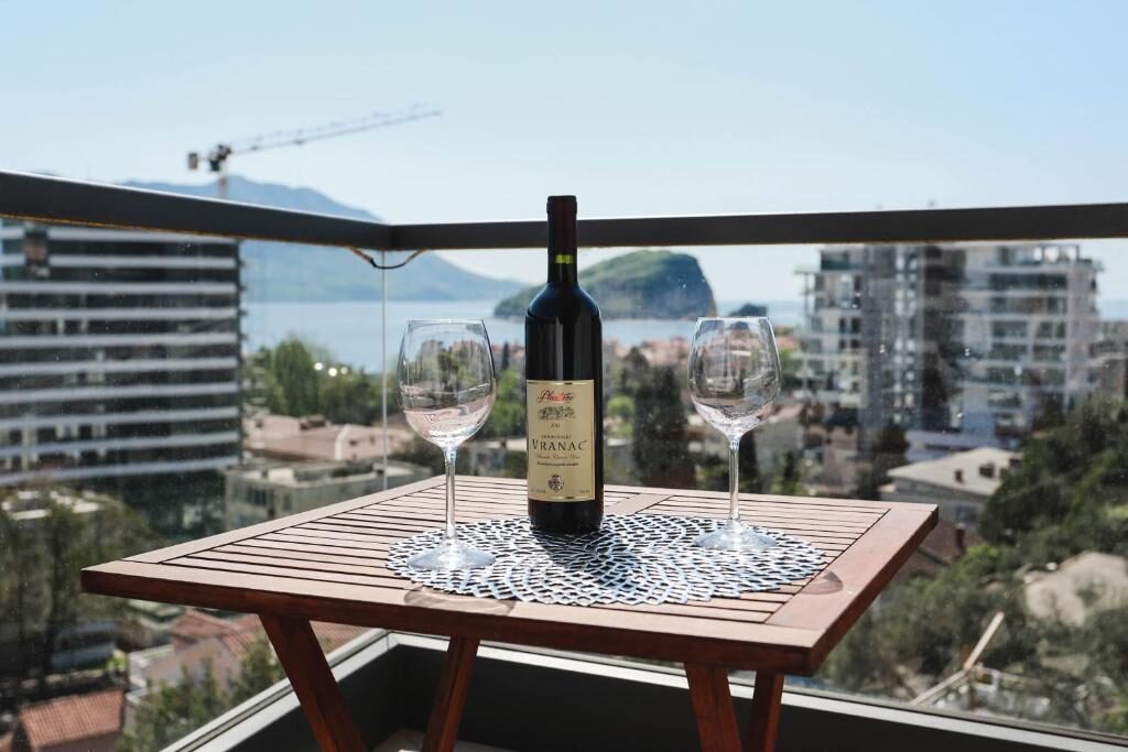 Wine and glasses on a balcony table above Budva bay